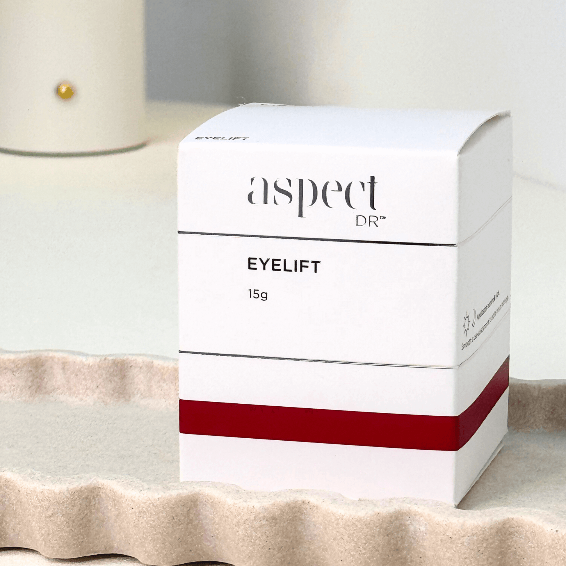 Eyelift Aspect Dr packaging on a textured surface with neutral background