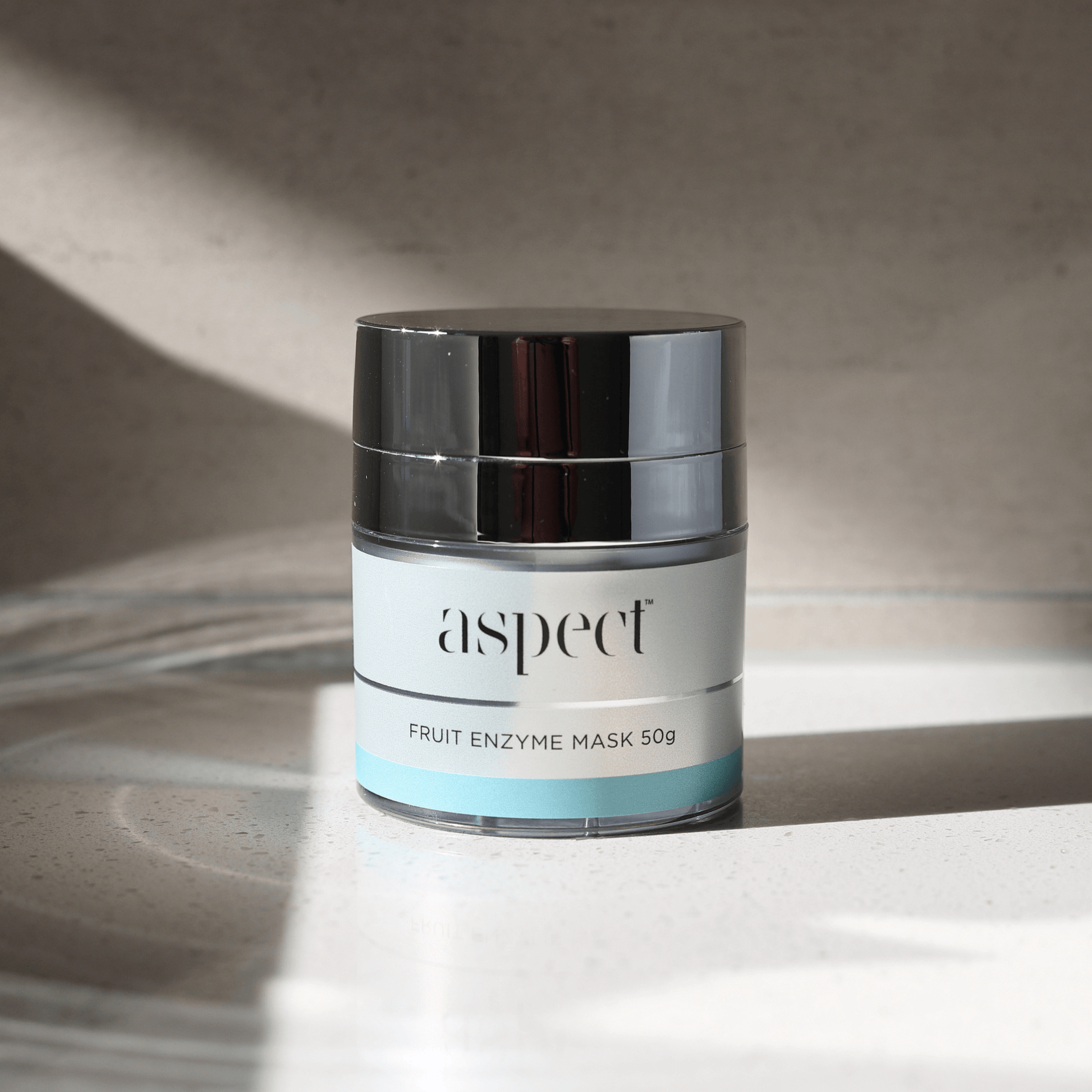 Jar of fruit enzyme mask with 'aspect' branding on a neutral background