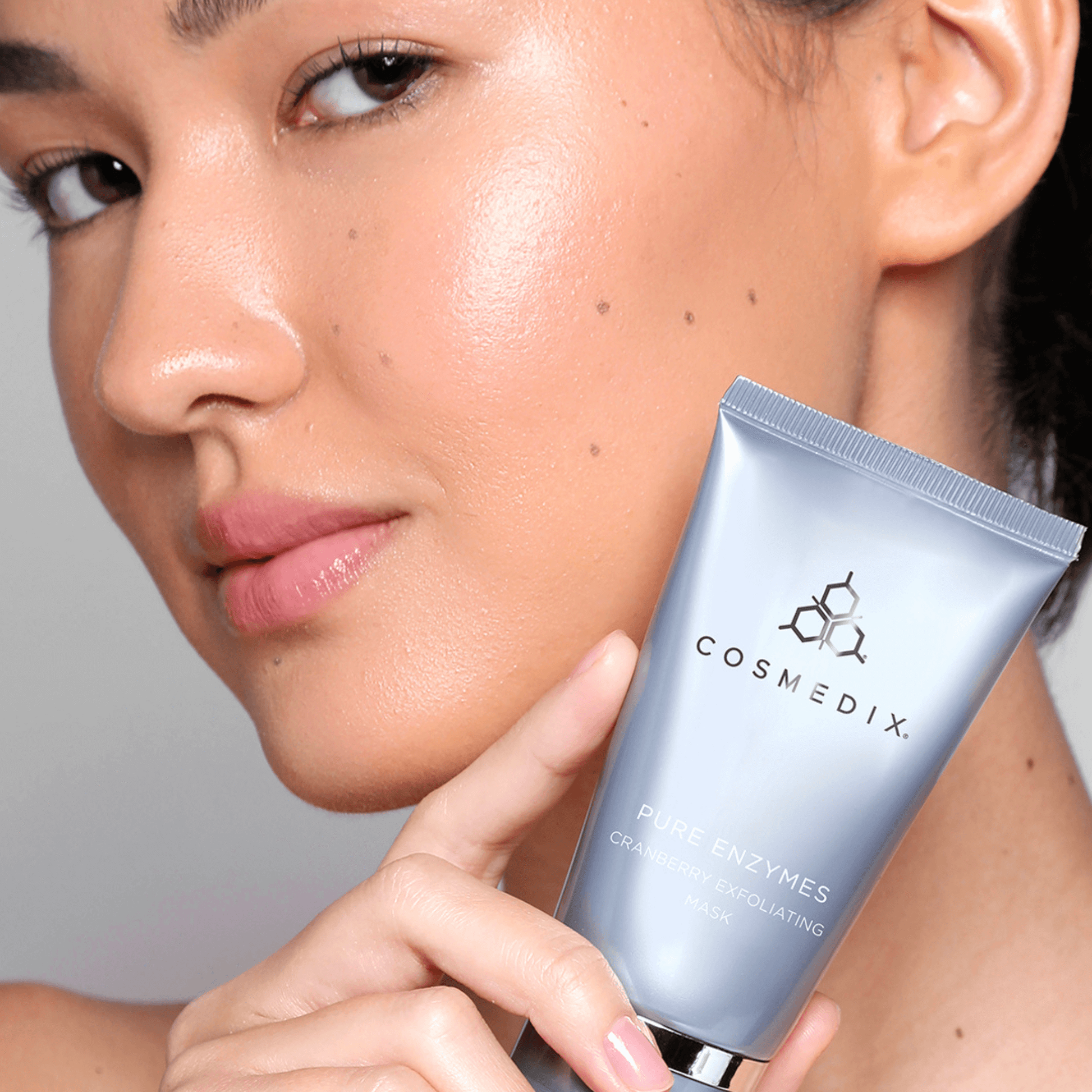 Person holding Cosmedix fruit enzyme mask close to their face