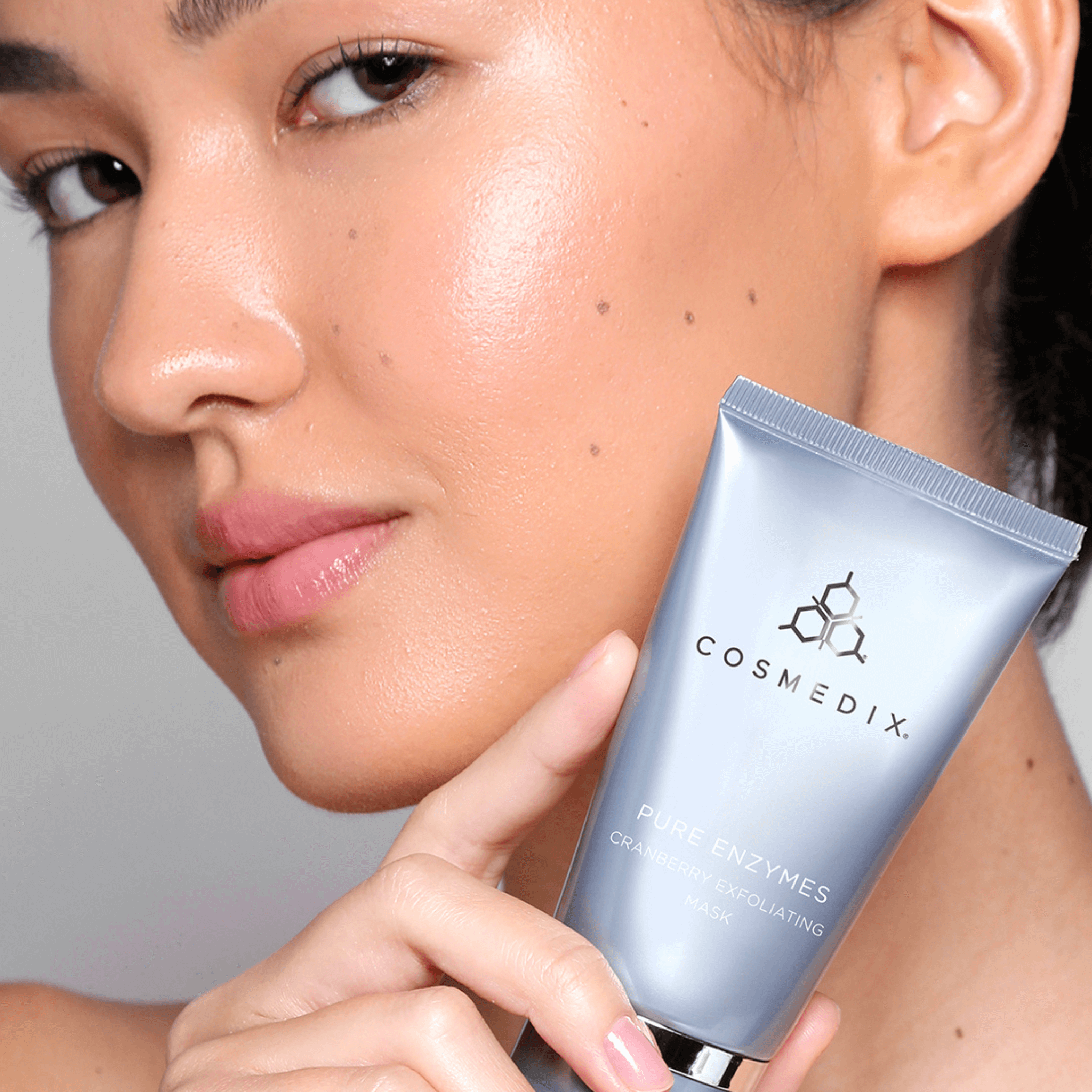 Person holding Cosmedix fruit enzyme mask close to their face