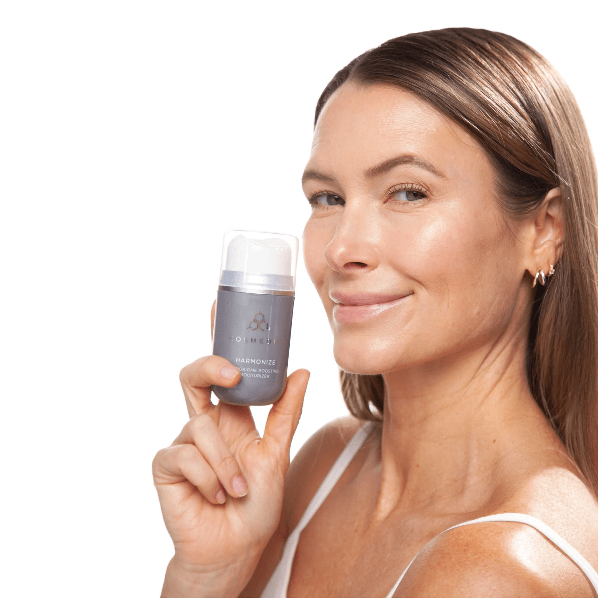 Woman holding Cosmedix harmonize with a plain background