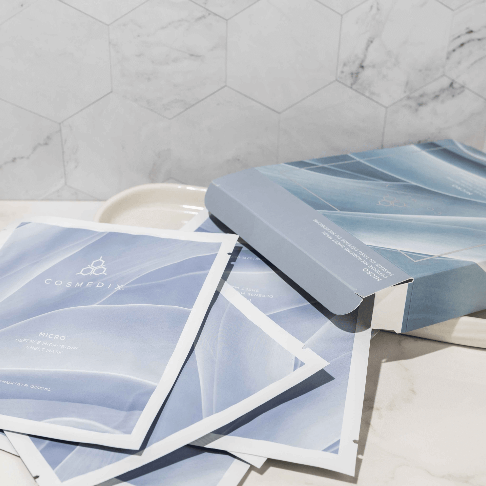 Cosmedix sheet masks on a marble surface with a branded Cosmedix box