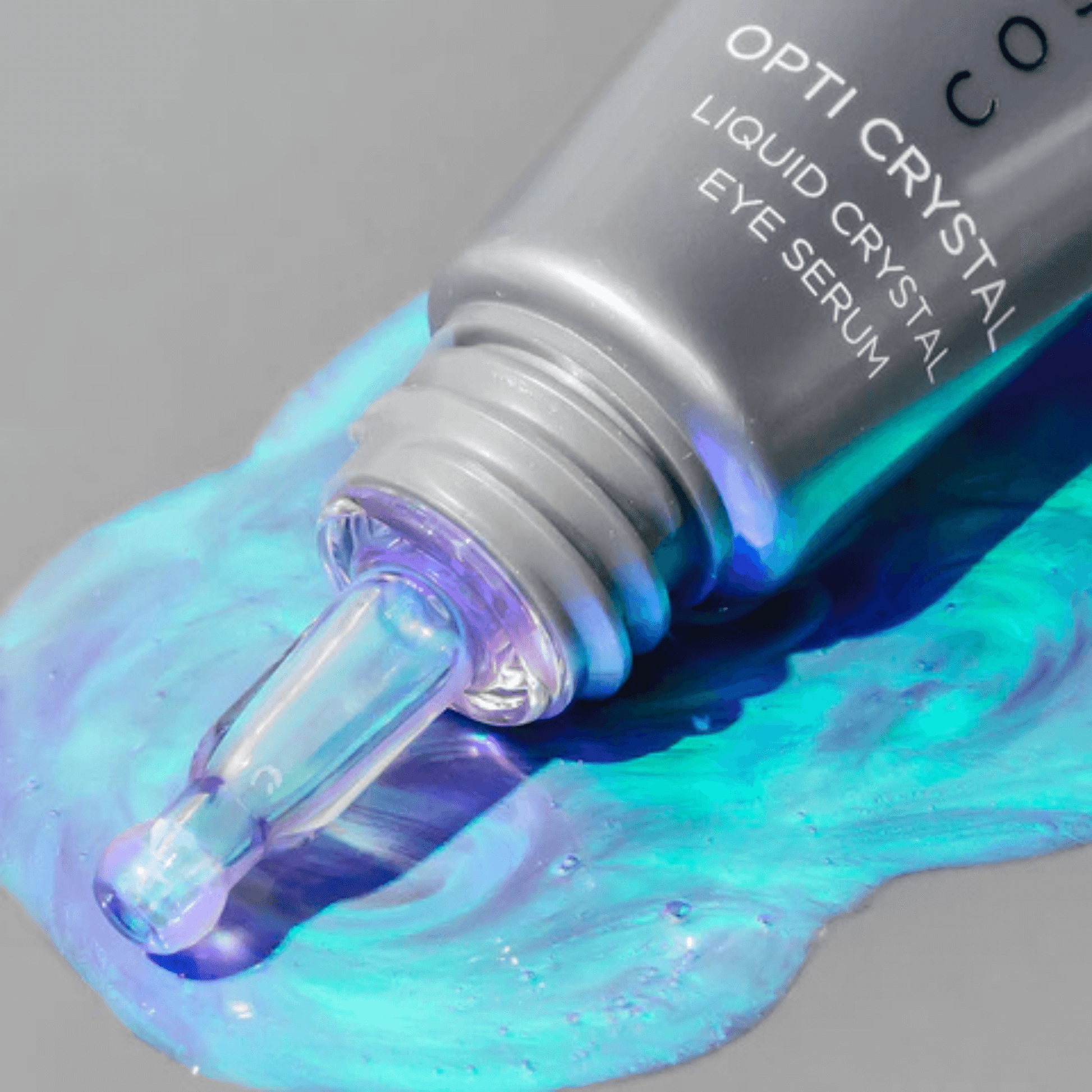 Opti Crystal liquid crystal eye serum bottle with blue and purple liquid on a grey background