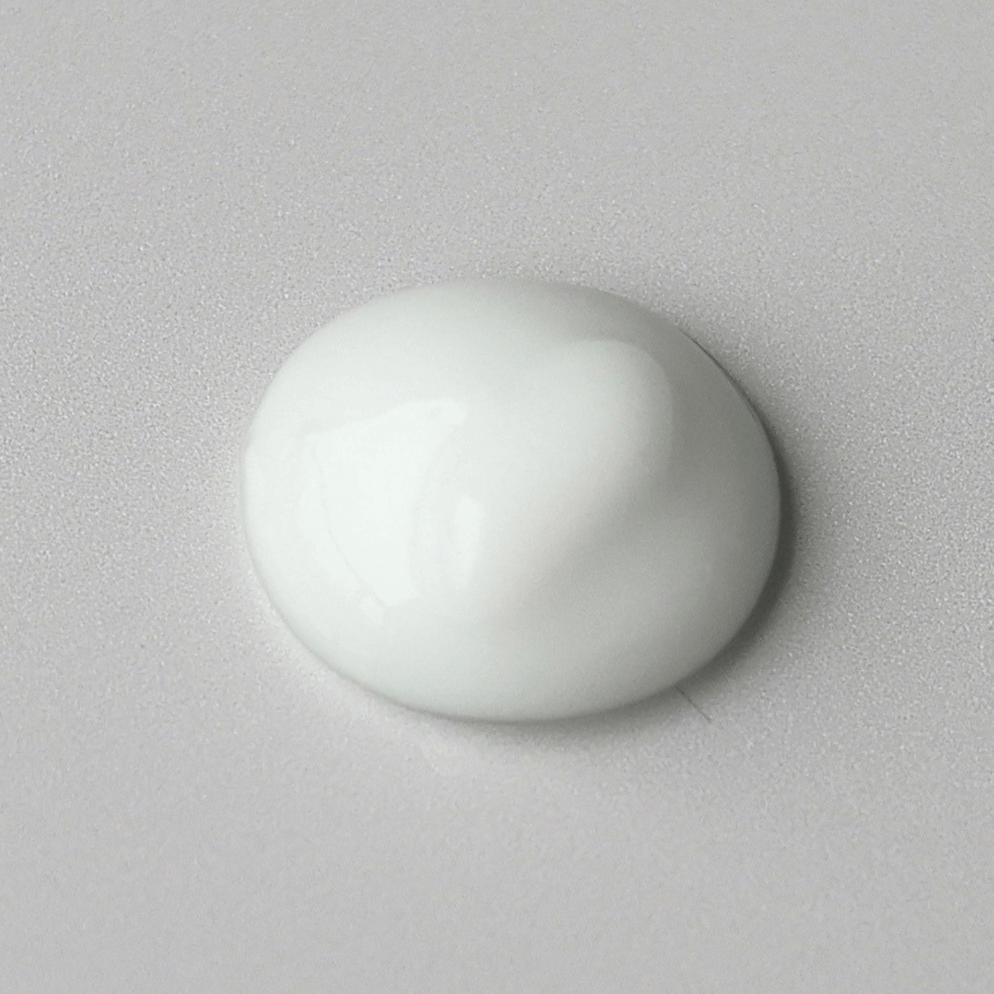 Optiboost Aspect Dr dollop of smooth, glossy white cream on a light grey textured background.