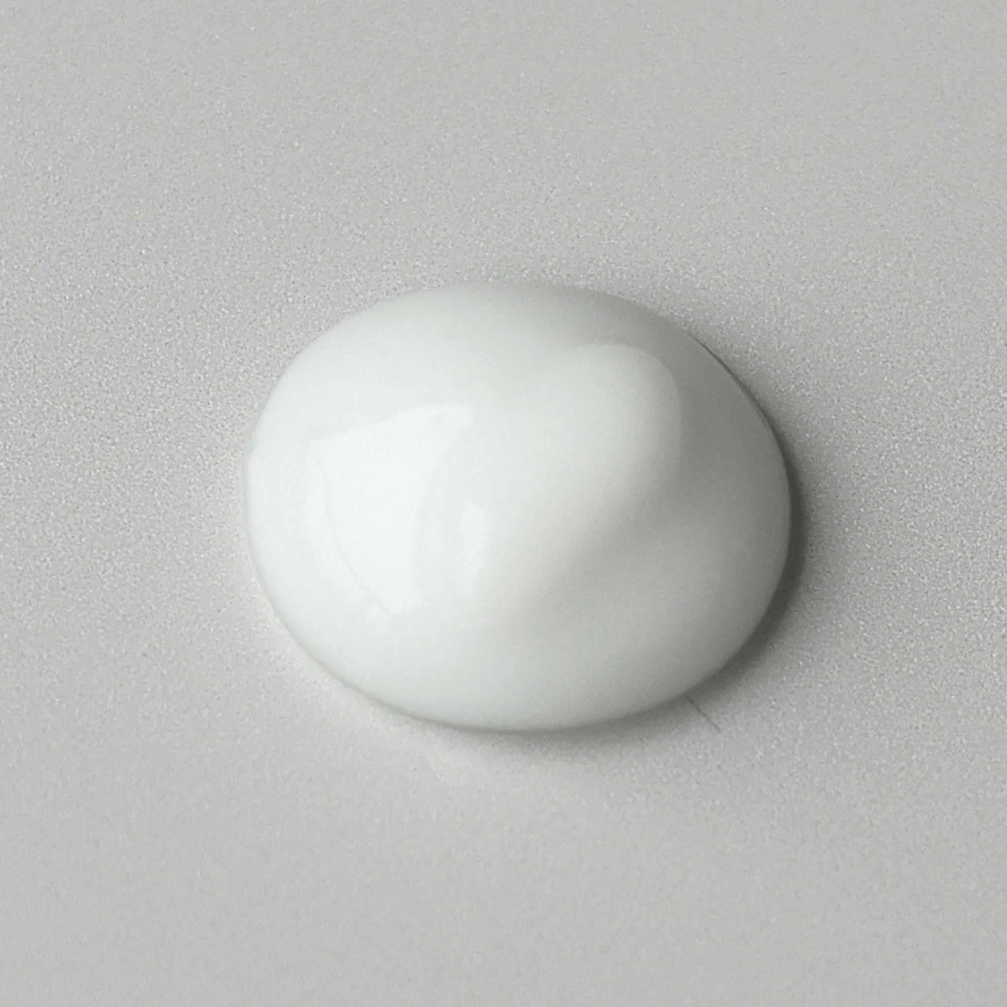 Optiboost Aspect Dr dollop of smooth, glossy white cream on a light grey textured background.