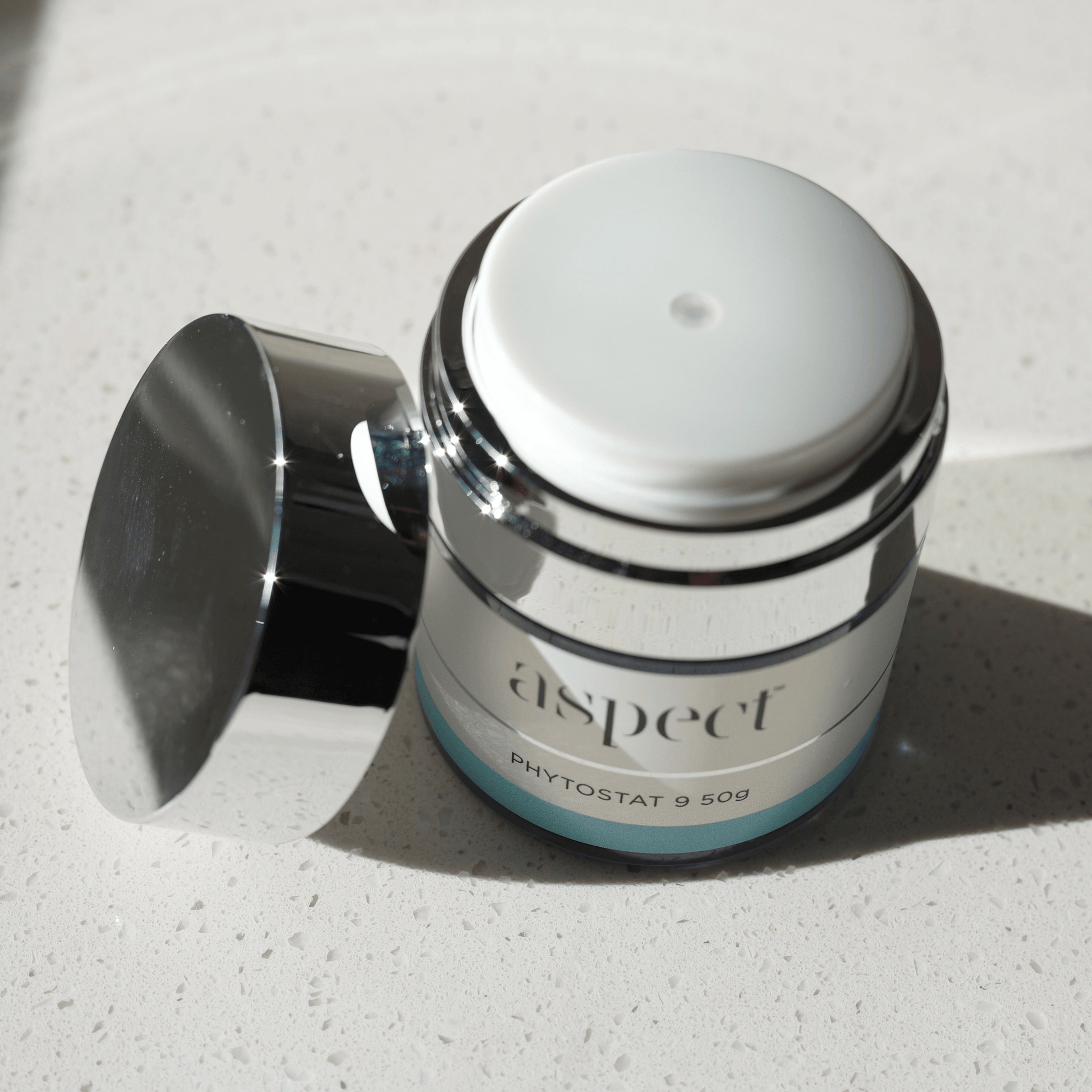 Skincare jar labeled 'aspect phytostat 9 50g' on a light surface