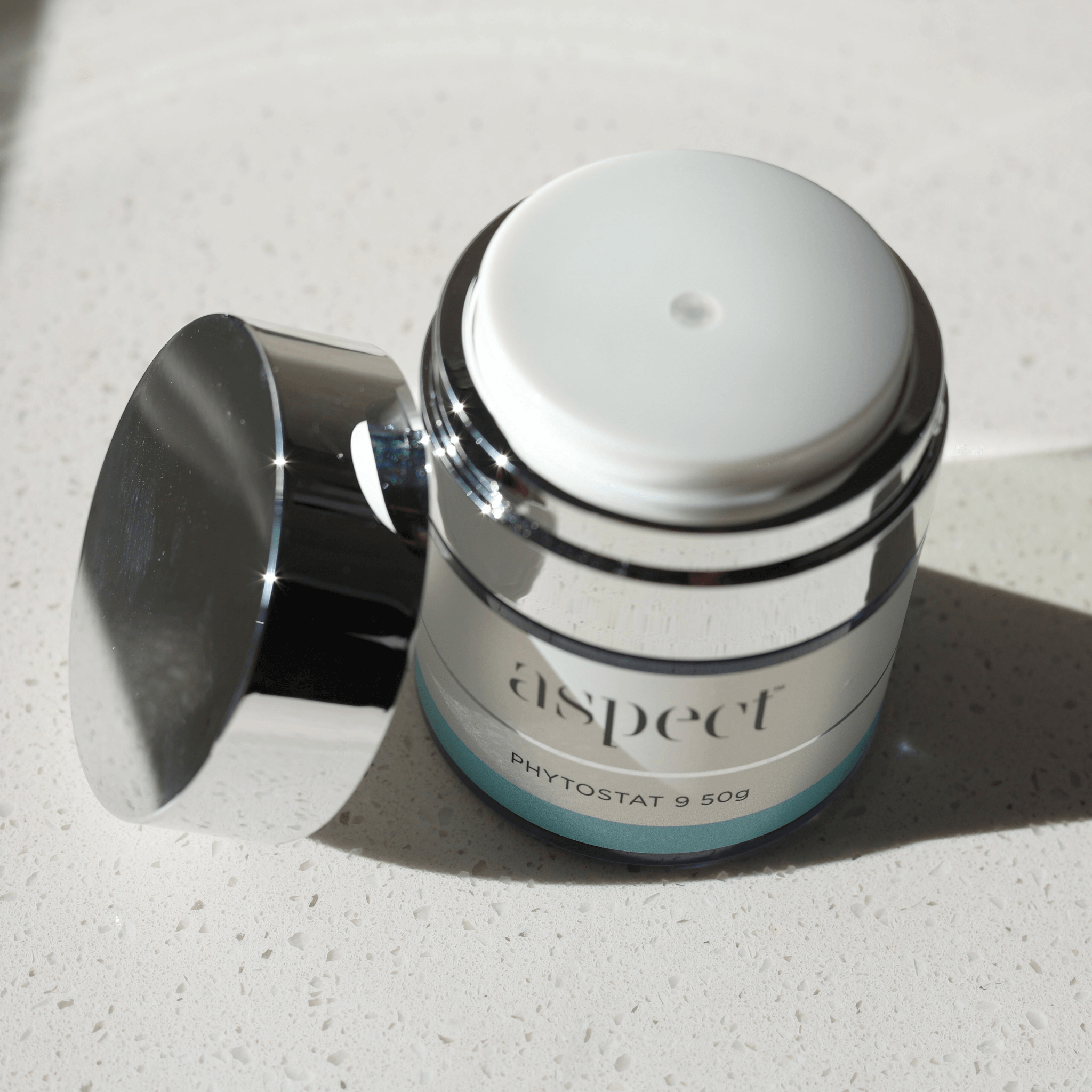 Skincare jar labeled 'aspect phytostat 9 50g' on a light surface