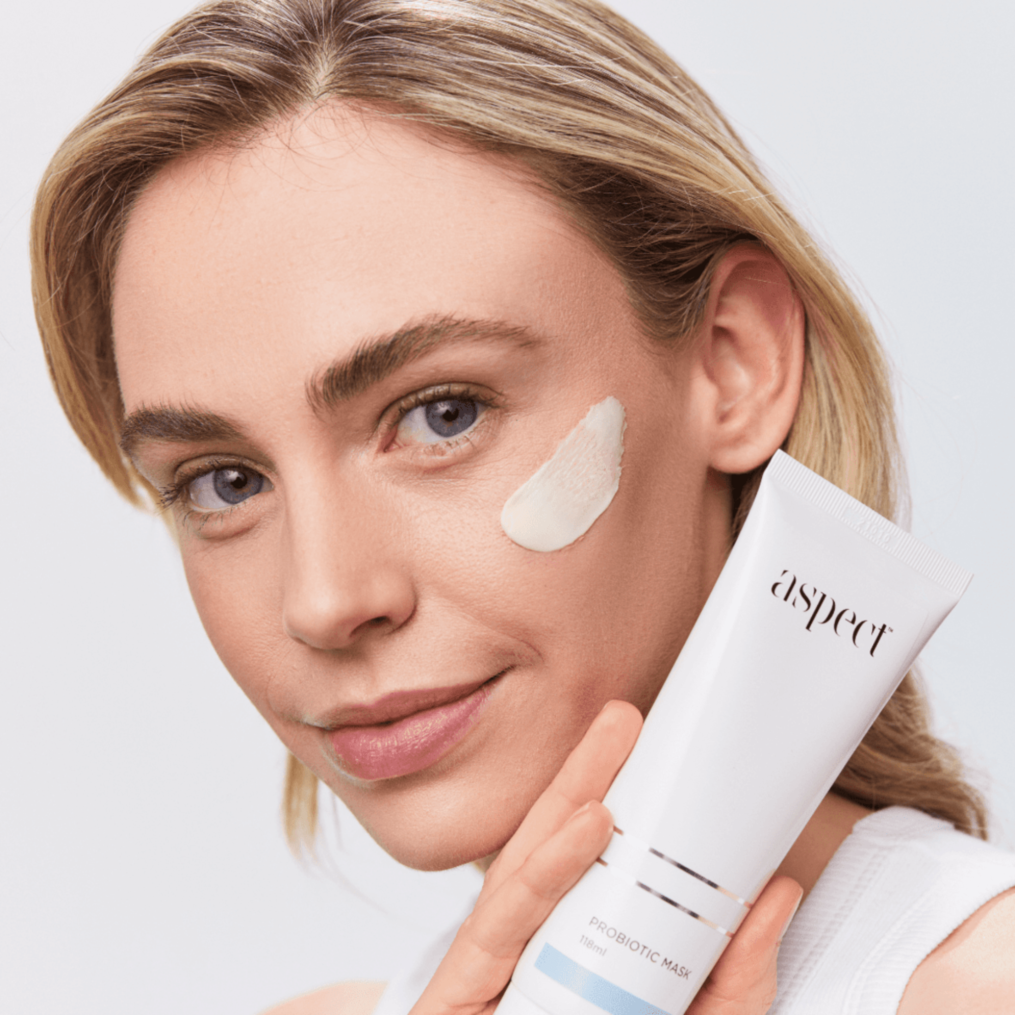 Woman applying aspect Probiotic mask to her face on white background