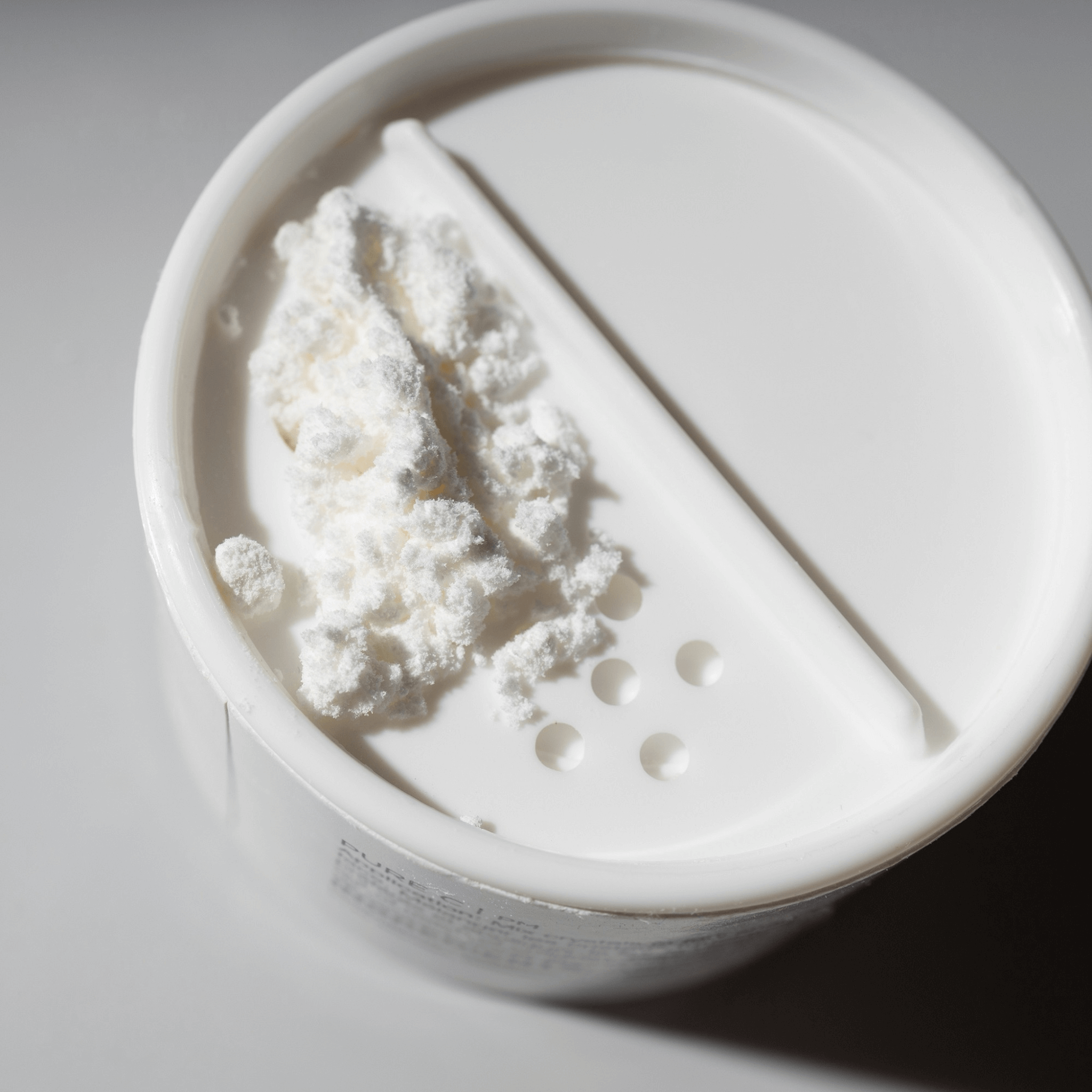 White Pure C Cosmedix powder in a container with a scoop on a light grey background