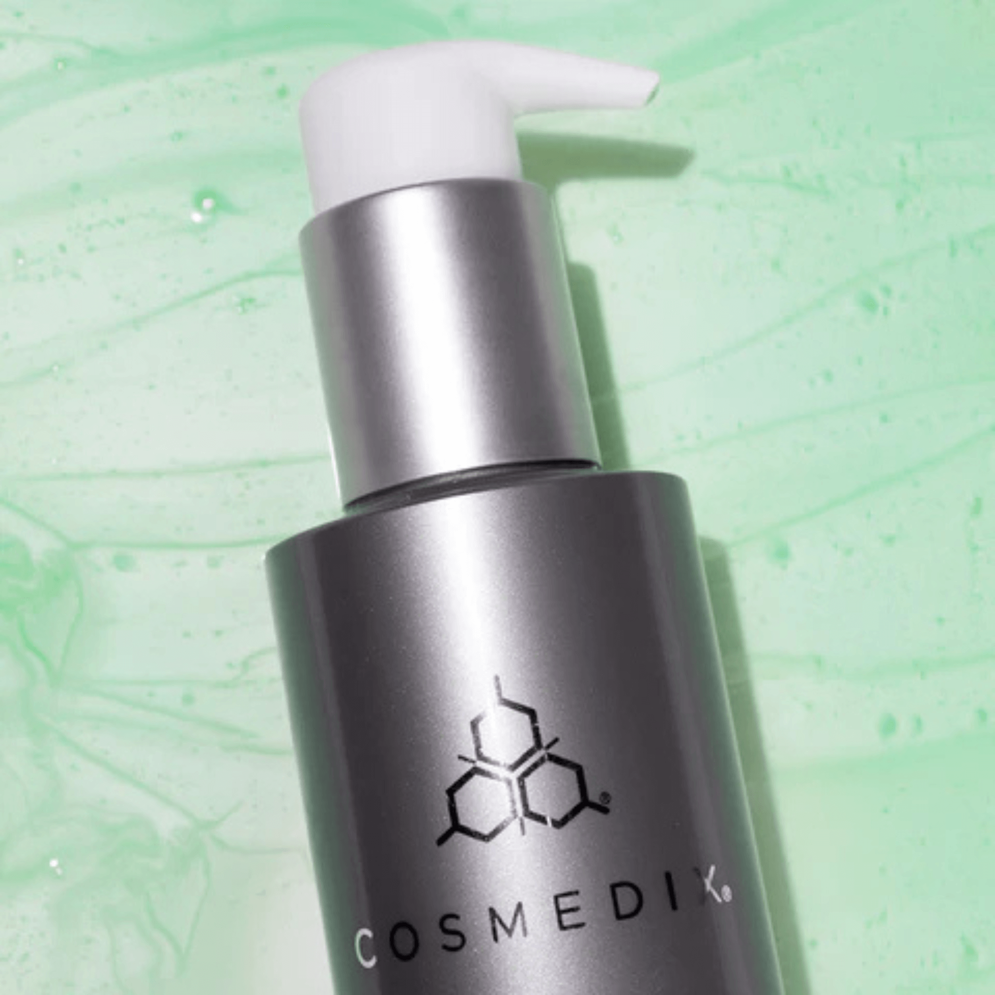 Cosmedix Purity Clean cleanser bottle with pump on a green textured background