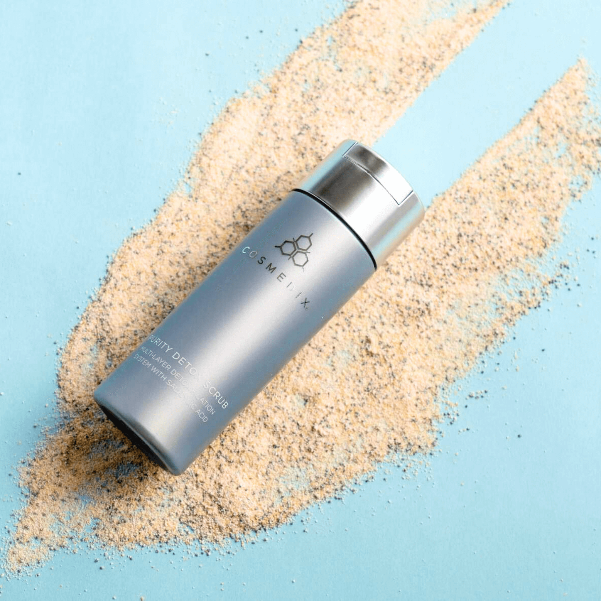 Cosmedix purity detox bottle with sand-like material on a light blue background