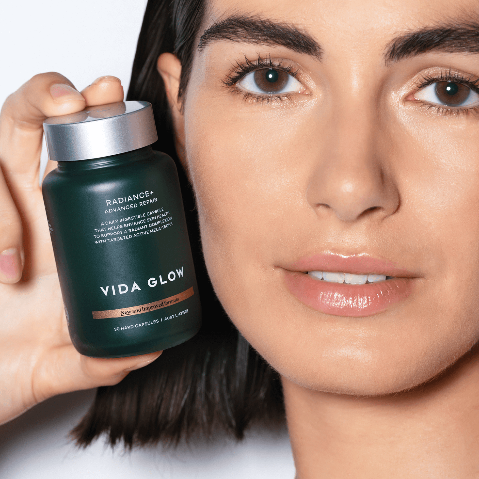 Woman holding a Vida Glow Radiance Plus bottle close to her face