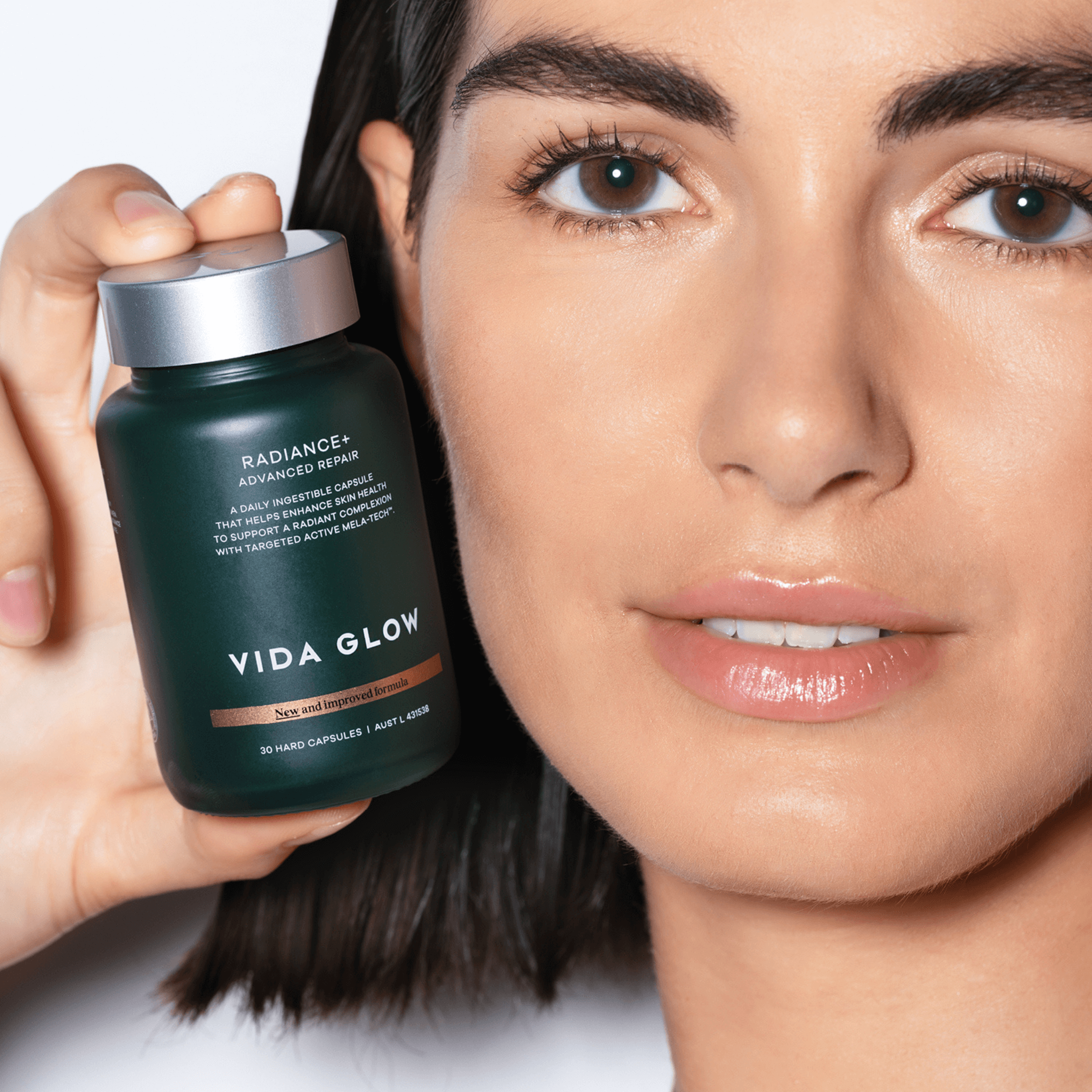 Woman holding a Vida Glow Radiance Plus bottle close to her face
