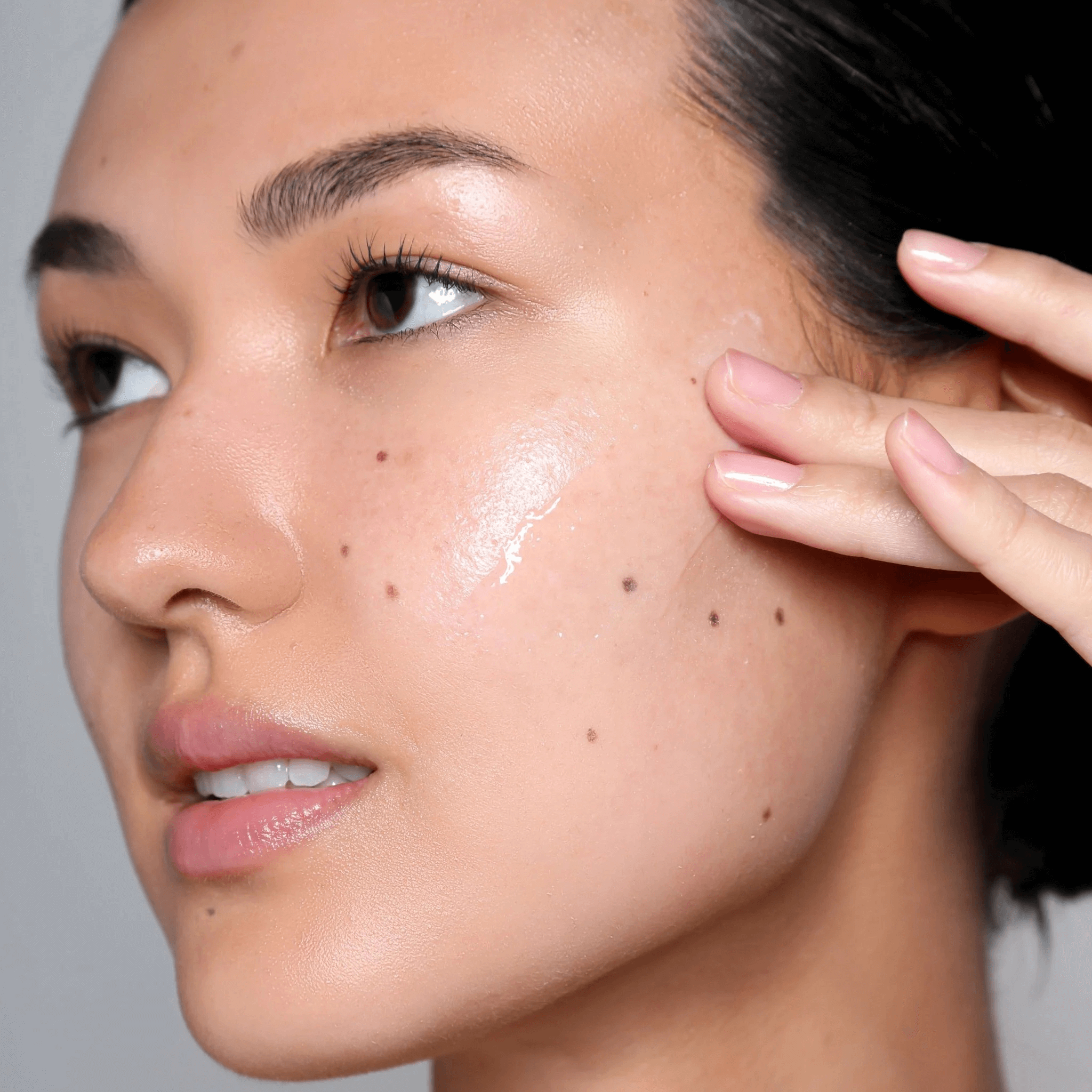 Close-up of a woman's face with Cosmedix Reboot Complex applied to face on a grey background