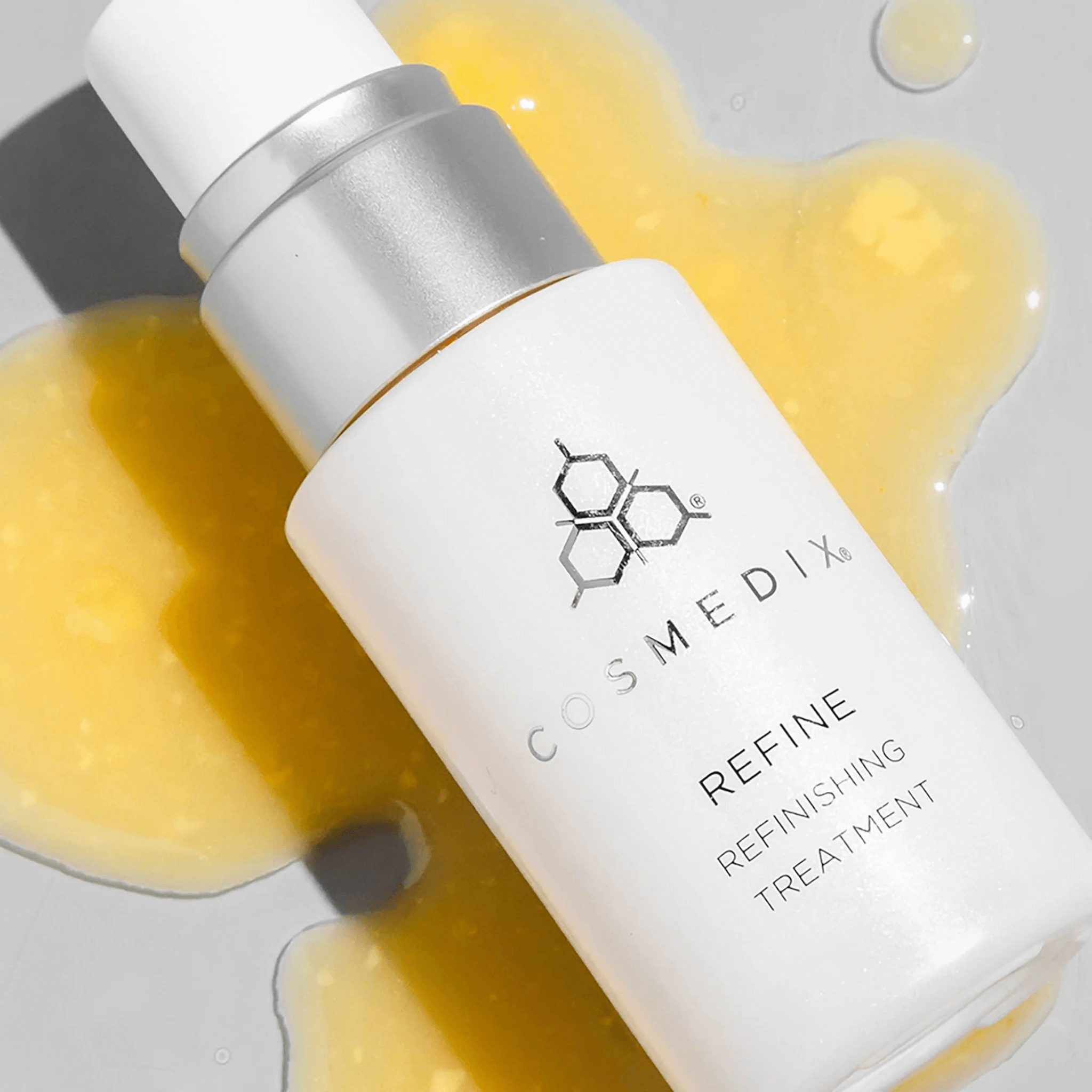 Cosmedix refine refinishing treatment bottle with dripped product on a grey background