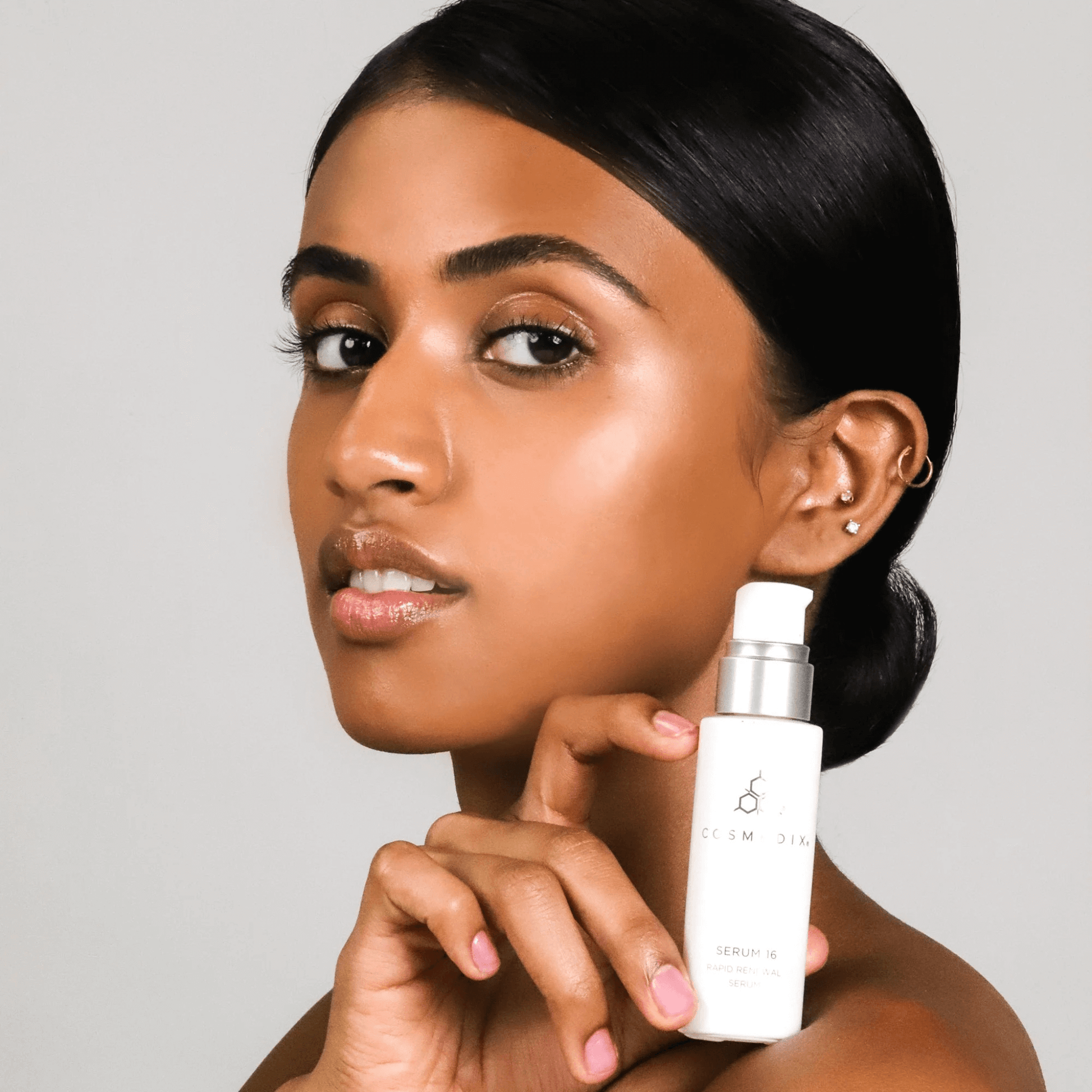 Woman holding Serum 16 bottle on light grey background