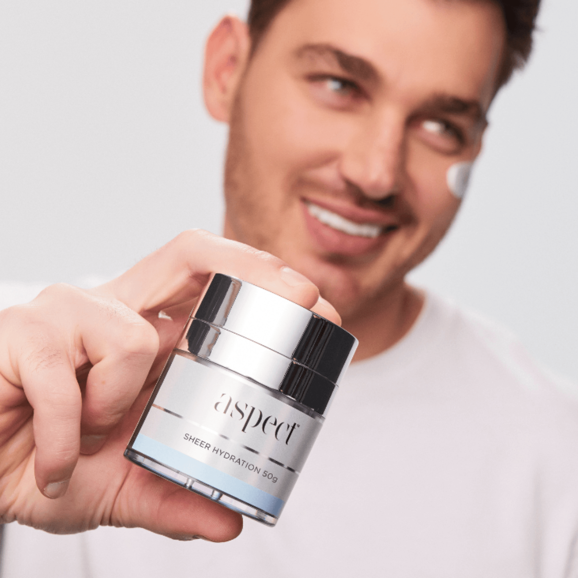 Man holding a jar of Aspect Sheer Hydration with a plain background