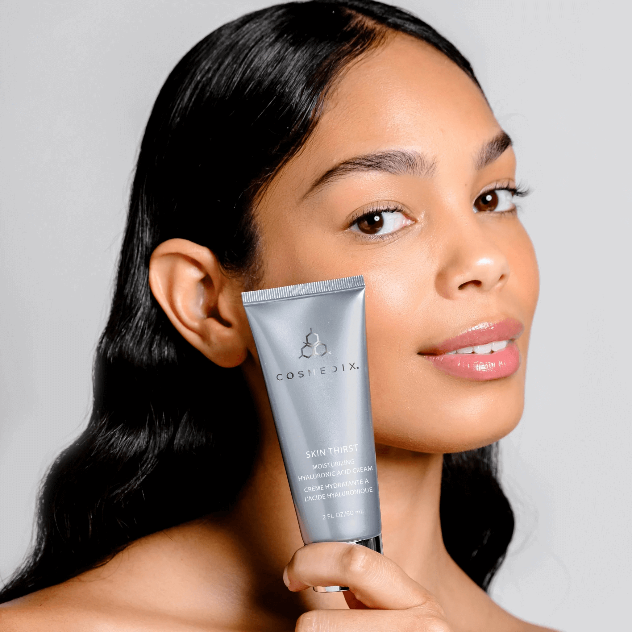 Woman holding a Cosmedix Skin thirst moisturising tube product against a neutral background