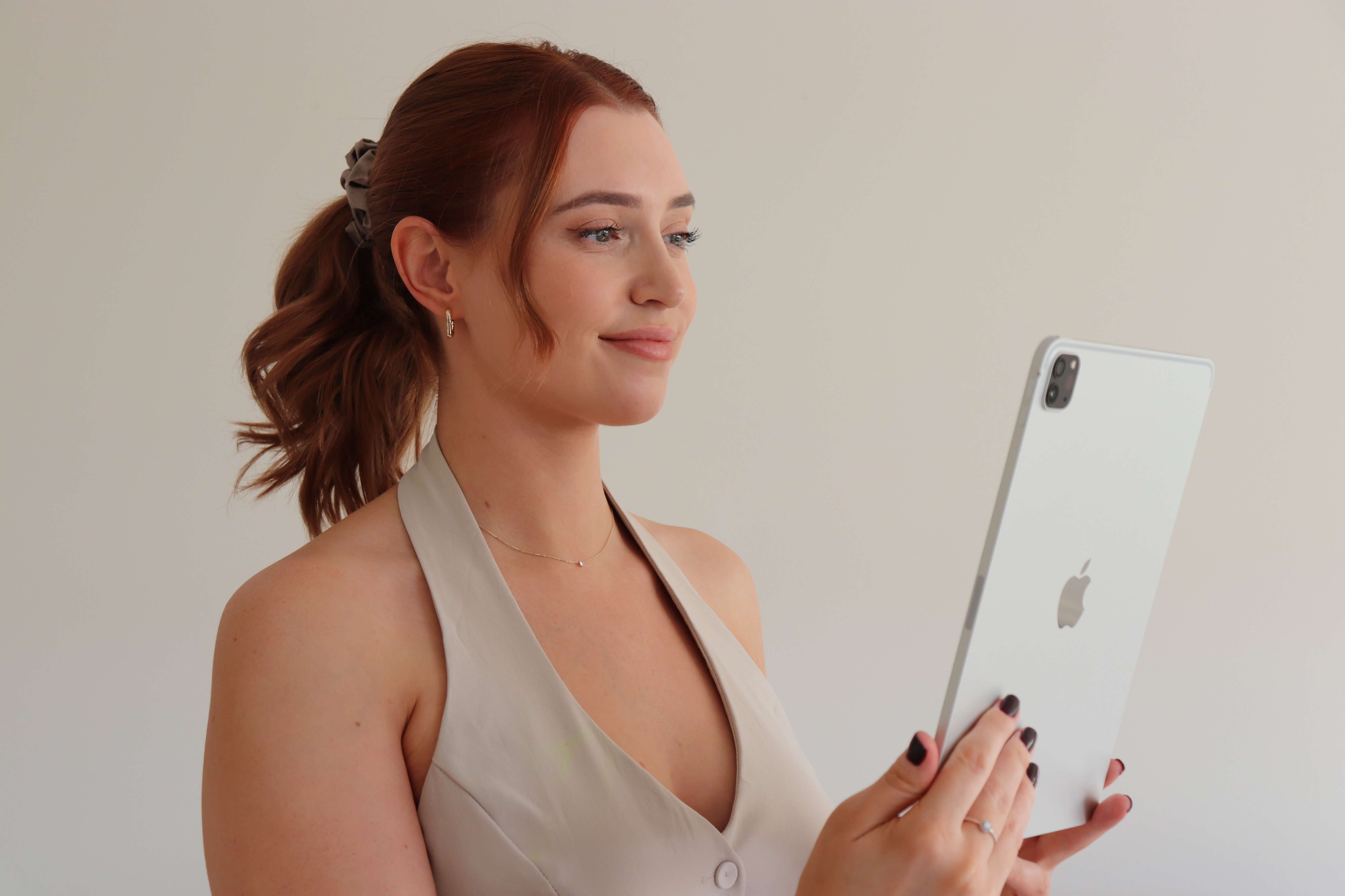 Woman holding a tablet with an Apple logo on a plain background