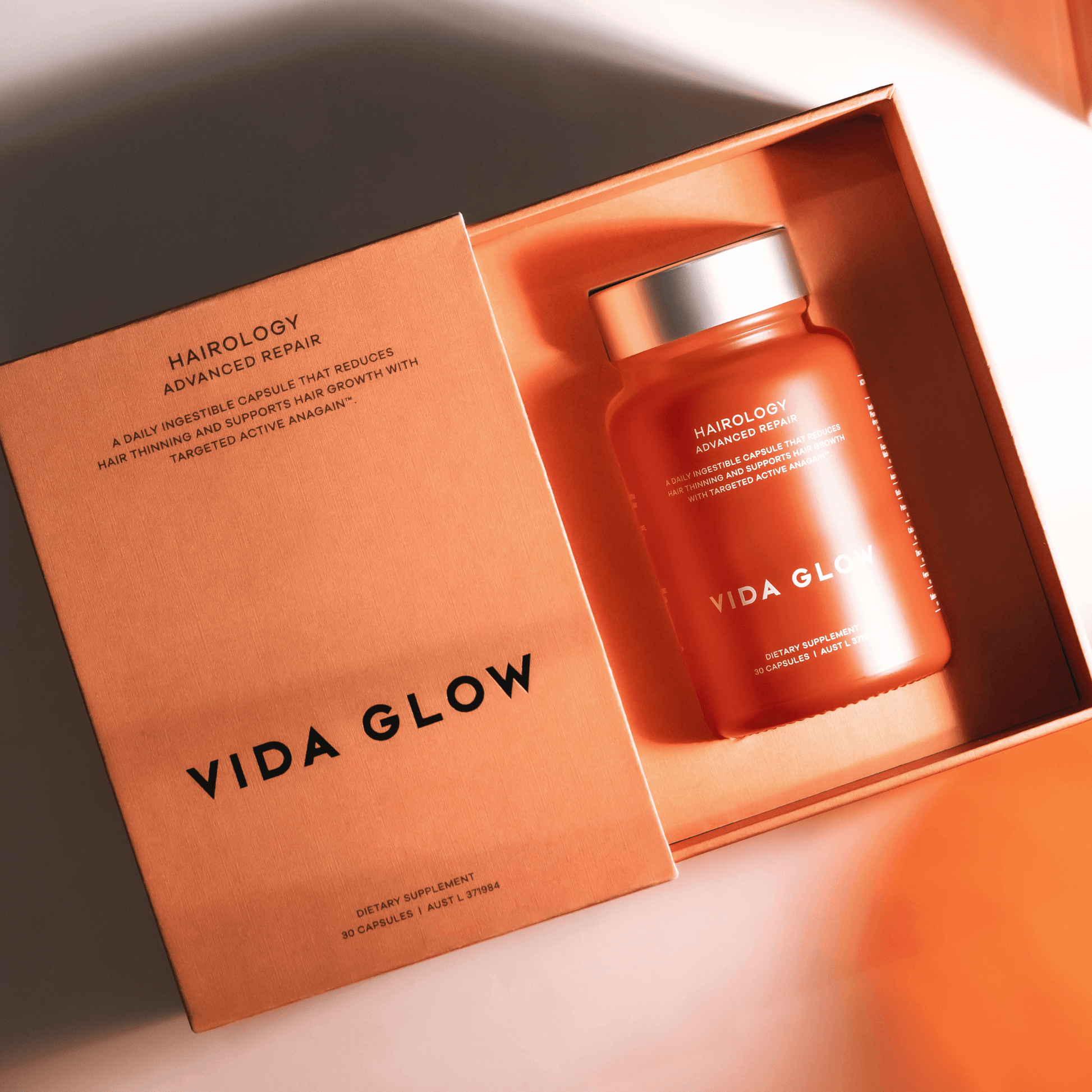 Vida Glow Hairology bottle in an open box on a light background