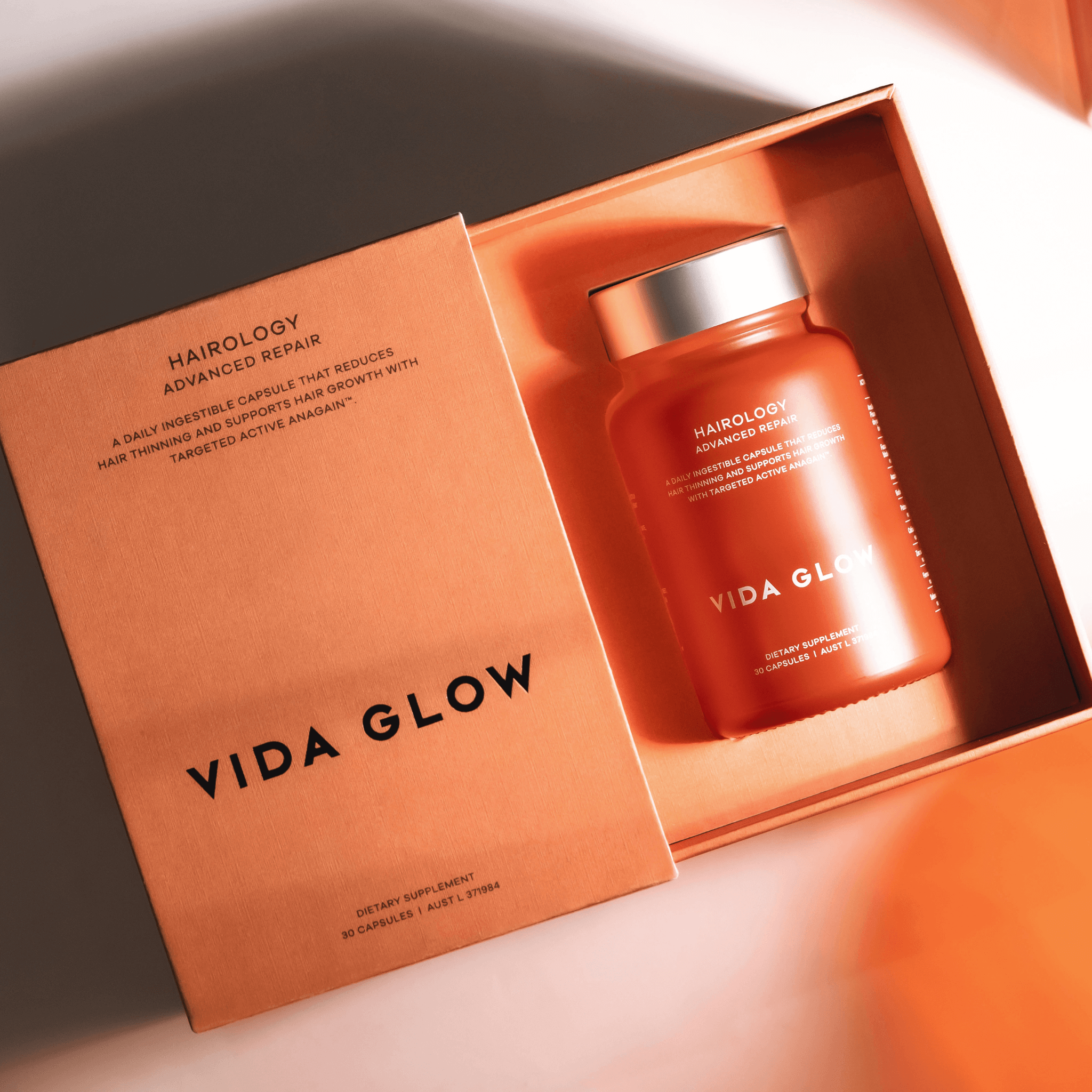 Vida Glow Hairology bottle in an open box on a light background