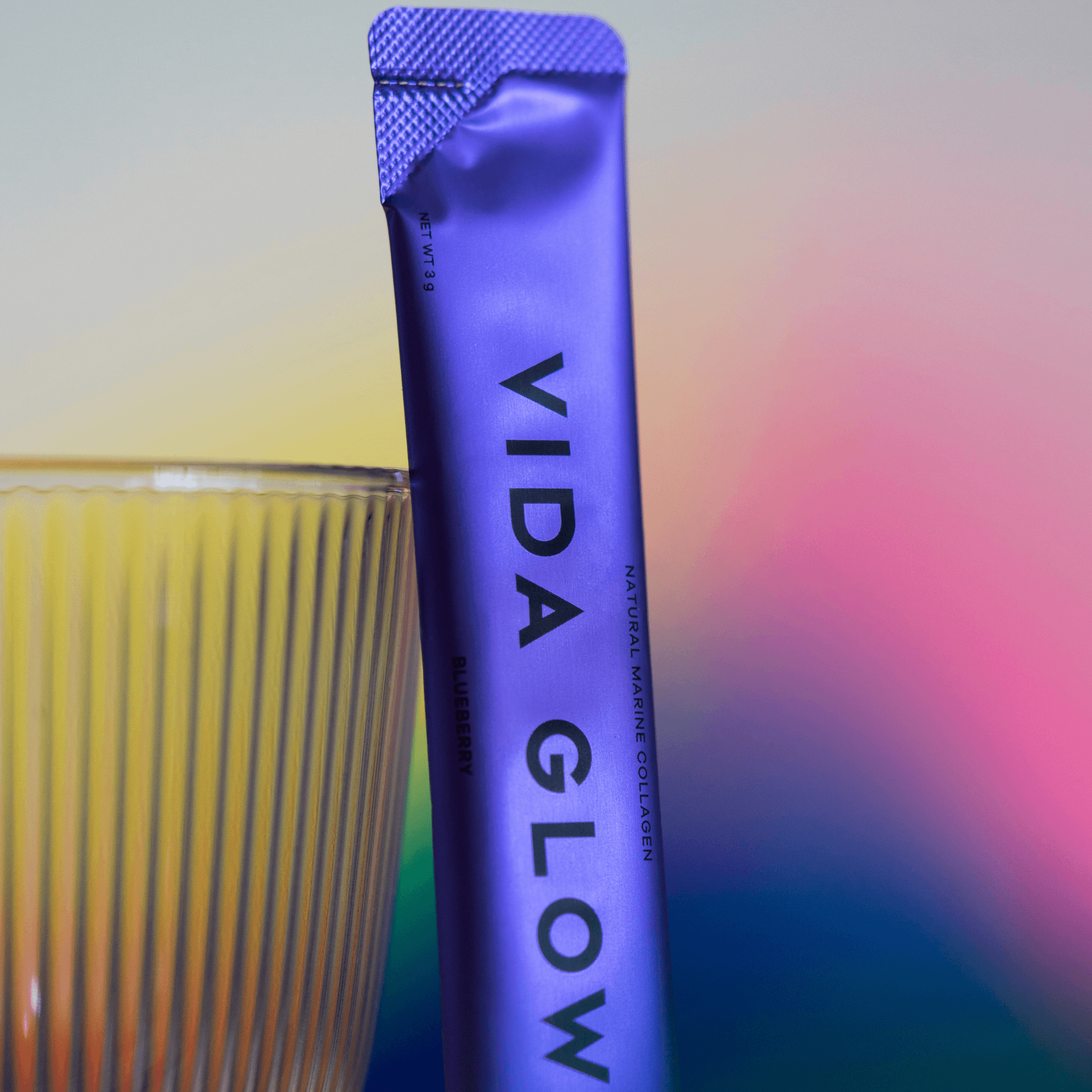 Vida Glow Blueberry sachet leaning on glass