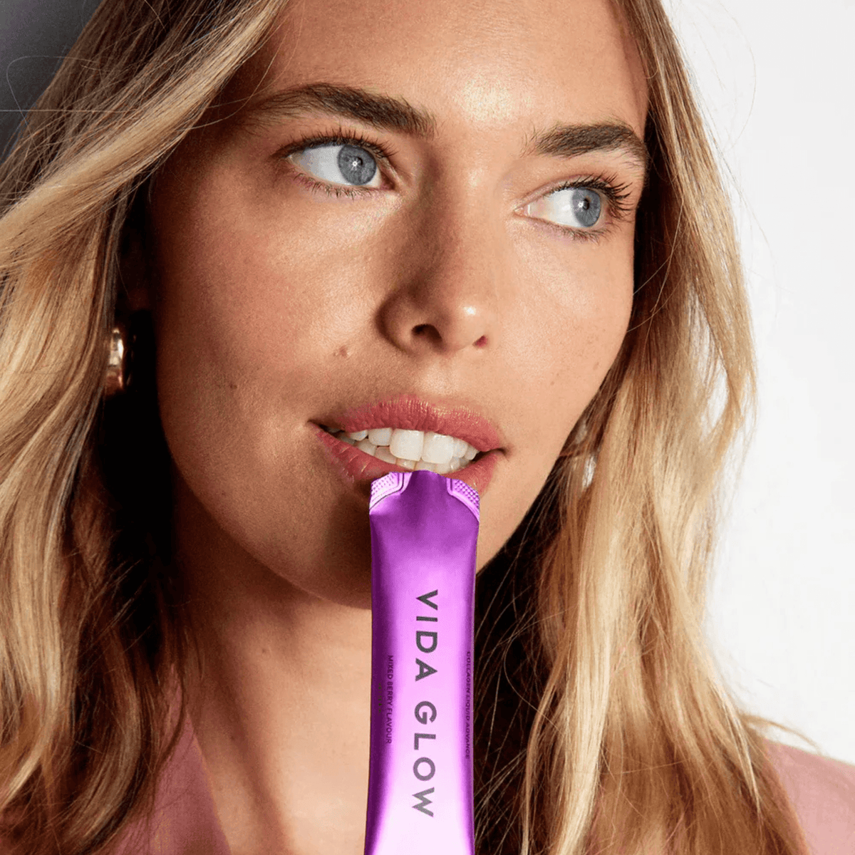 Model holding an open sachet of Vida Glow Liquid Collagen advanced