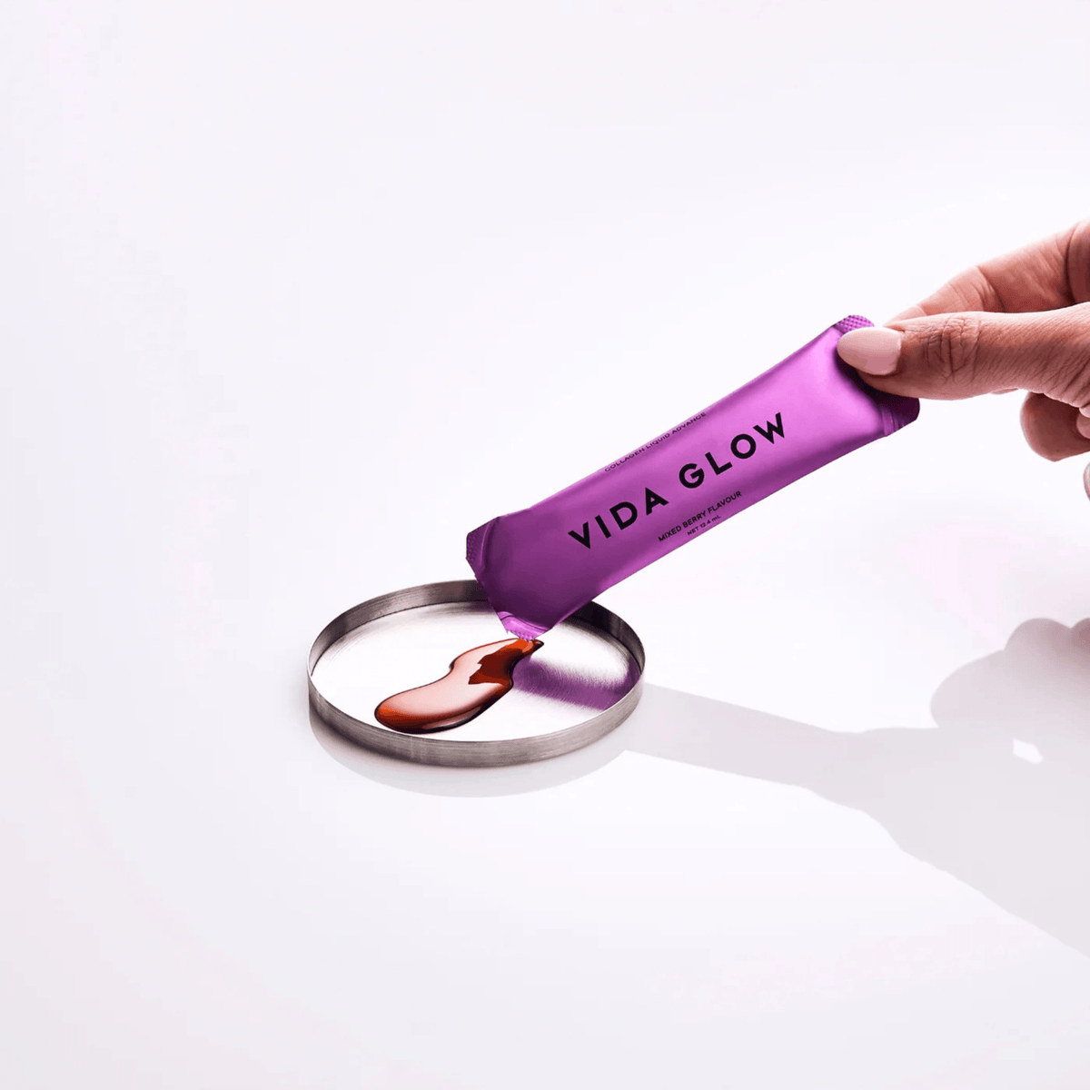 Vida Glow Liquid Collagen sachet poured into a circular metal dish