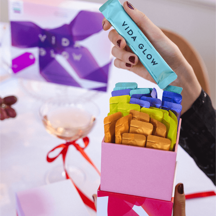 Hand holding a box of colourful Vida Glow products with a blurred background