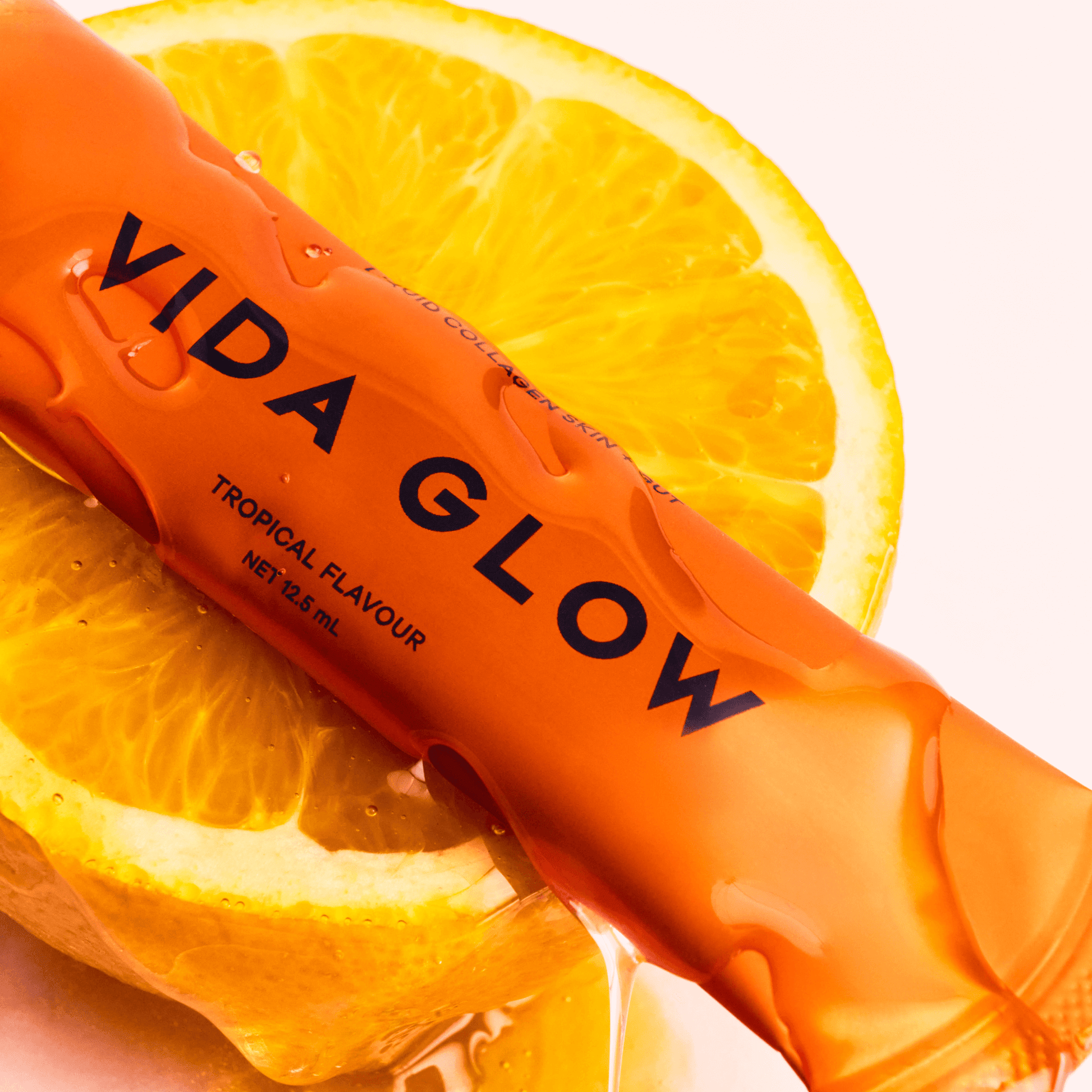 Vida Glow tropical flavour sachet on an orange slice with a white background