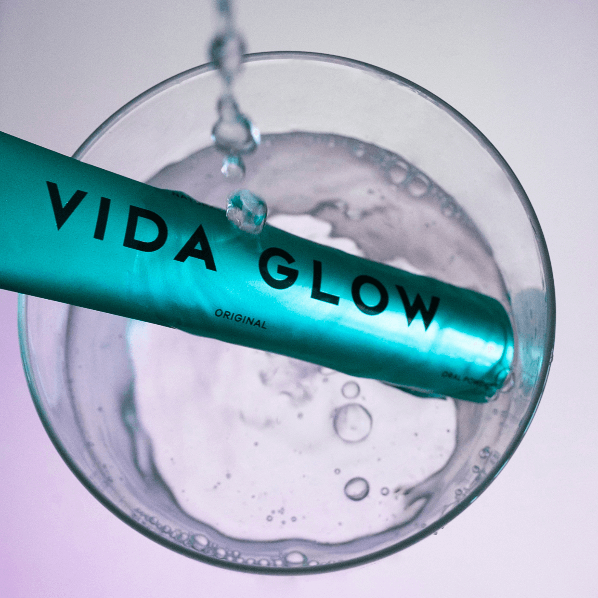 Vida glow original collagen powder in glass of water with water droplets